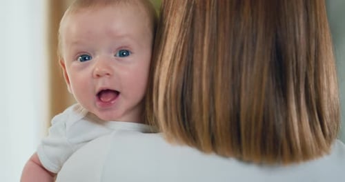 Mother holding smilling baby toddler boy. Young mom holding newborn baby. Family at home, woman with