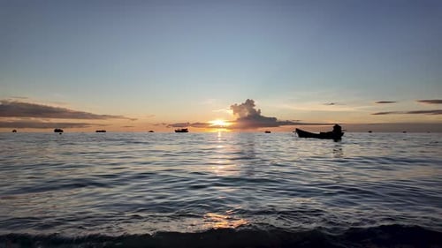 Idyllic scene capturing a beautiful golden hour sunset over the ocean, with boats silhouetted agains
