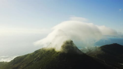4K-Drohnenaufnahmen von Wolken rund um einen Berggipfel entlang der Küste