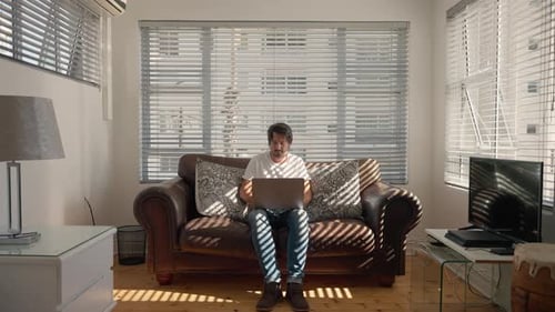 Adult Using Laptop on Couch in Bright Home