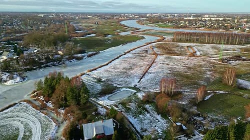 Luftdrohne über der Stadt am Stadtrand mit hellblauem Flusswasser, das im Winter zugefroren ist