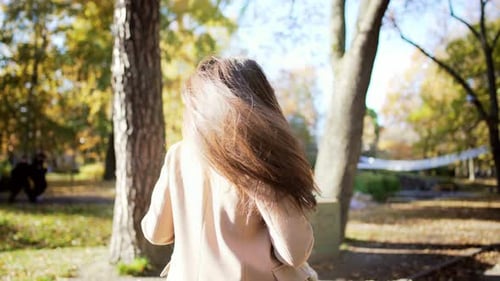 Side View Portrait of Caucasian Beautiful Young Woman Going Forward in Park with Glass of Coffee and