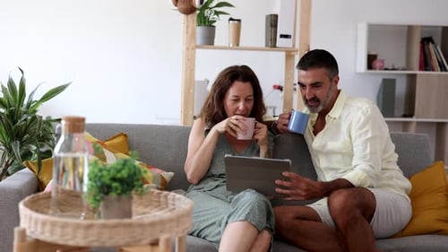 Couple Drinking Coffee Watching Tablet at Home