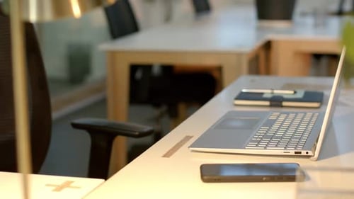 Laptop lid rising in office with camera panning over smartphone and notebook preparing for work