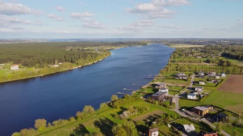 Slow drone flyover shows Daugava River meandering past Katlakalns residential area toward Riga Gulf