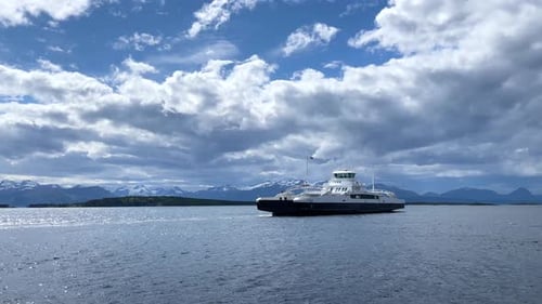 Ferry navigates serene waters with stunning mountain backdrop in coastal region