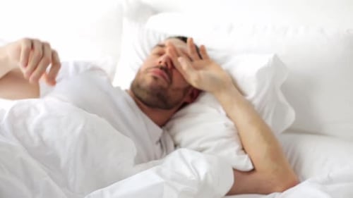Man Waking up and Stretching in Bed