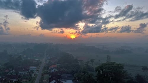 A Sunrise Over A Village Shrouded In Mist With Dramatic Clouds Overhead