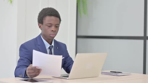 Young Adult Analyzing Documents in Workplace