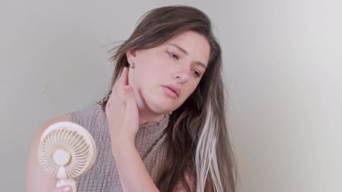 Woman Cooling Herself with a Portable Fan