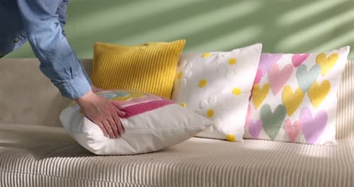 Woman arranging pillow on sofa at home, closeup