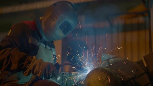 Schweißer mit Schutzmaske verschmilzt Metall in der Werkstatt
