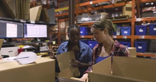 Female Workers With Clipboard Inspecting Boxes For Shipping In Warehouse Slow Motion