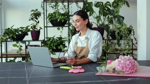 Woman Working on Laptop Surrounded by Plants
