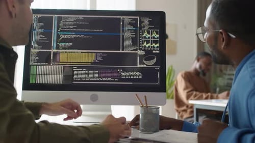 Two Adults Analyzing Code on Computer Screen
