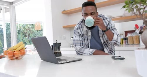 Man Working From Home Drinking Coffee at Counter