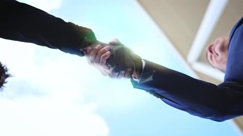 Interracial business partners seal an agreement deal with handshake from below angle view. Digital n
