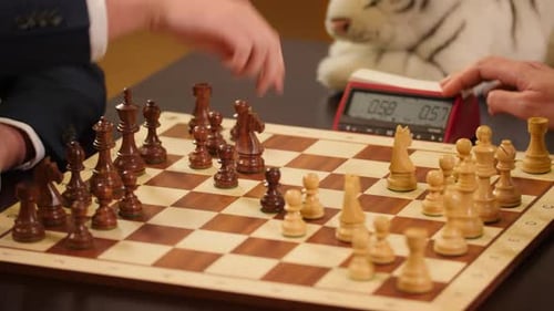 Schachgroßmeister spielen Schnellschach mit einer Schachuhr und einem Schachbrett aus Holz.