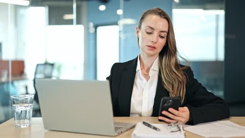 Businesswoman at Desk with Laptop and Smartphone