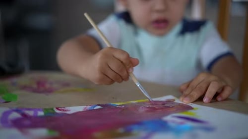 Closeup of child hand painting with watercolor and paintbrush during creative artistic session,