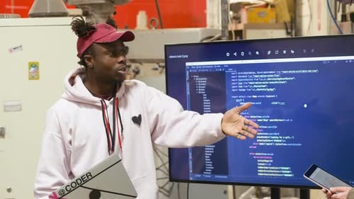 Young man explains coding on screen in workplace