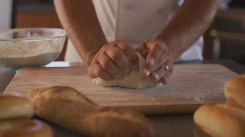 Chef kneading fresh bread dough preparing delicious food at a bakery kitchen