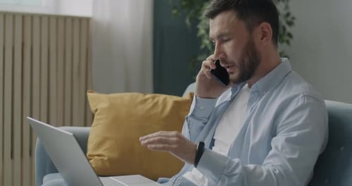 Man Working from Home on Laptop and Phone