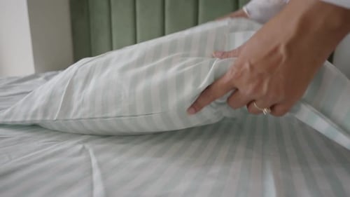 Woman Making Bed, Putting Pillow in Pillowcase