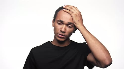 Man Holding Forehead in Discomfort on White Background