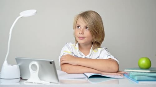 Middle School Smiling Student Boy Sitting at Desk Remote Studying Writing Book Homework and Tablet