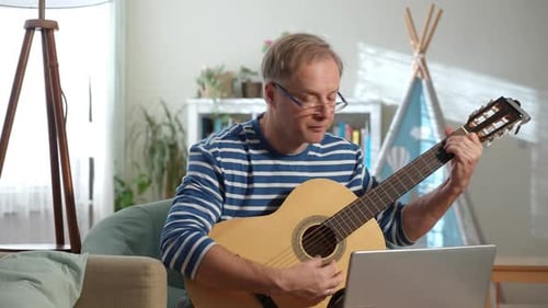 Ein Mann mittleren Alters spielt eine Akustikgitarre