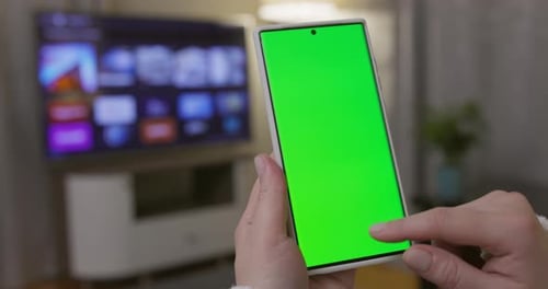 Closeup of Woman Hands Holding Smartphone with Green Screen in Vertical Position