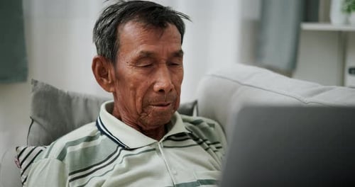 Senior Man Using Laptop on Couch Indoors