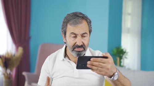 Man Using Smartphone with Surprised Expression Indoors