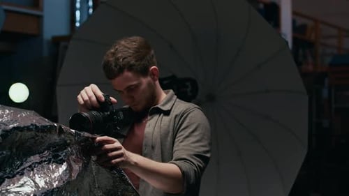 Jeune photographe masculin au travail dans un studio professionnel bien équipé