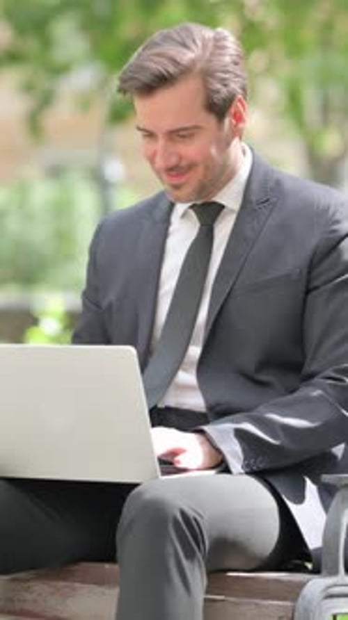 Man in Suit Works on Laptop in the Park