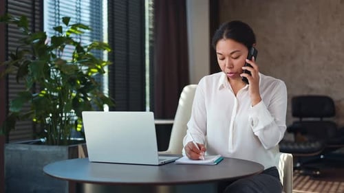 Woman Working at Laptop, Talking on the Phone
