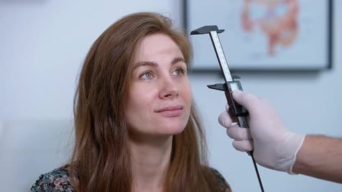 Gros plan d'une femme caucasienne positive regardant un médecin méconnaissable mesurant le visage avec Vernier