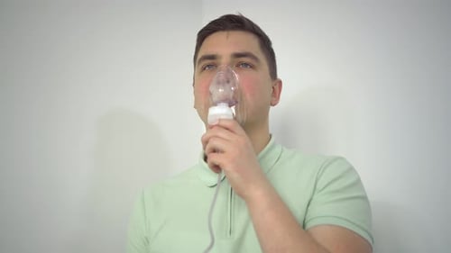 Un jeune homme respire à l'aide d'un inhalateur en gros plan Un homme portant un masque à oxygène est traité pour un
