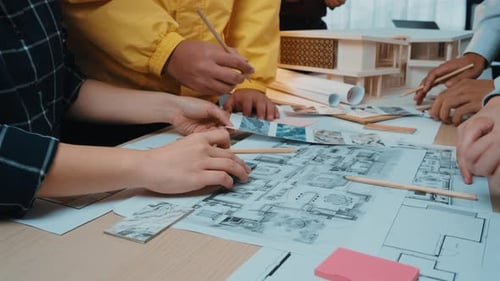 Architects Collaborating on Blueprints in a Bright Workplace