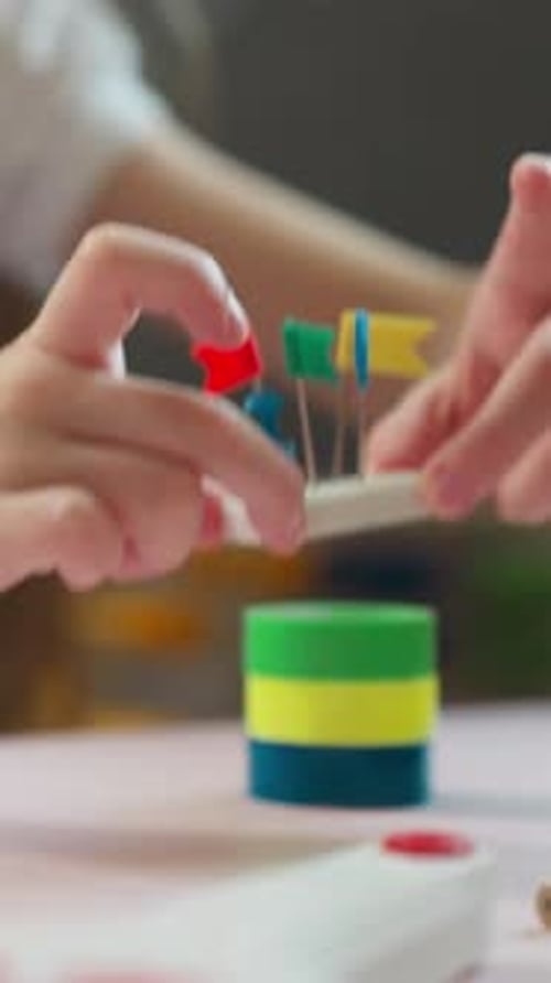 Una niña construye una torre con una goma de borrar y pequeñas banderas en la parte superior