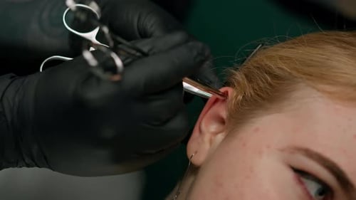Piercing studio interior - piercing master makes a piercing to a girl, ear piercing