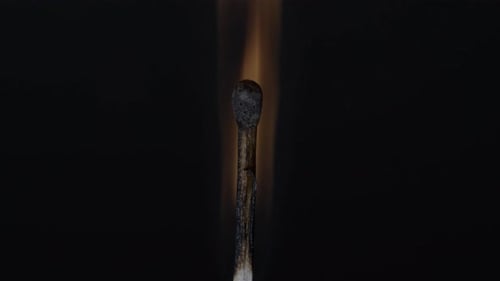 Burning a matchstick in black background - close up