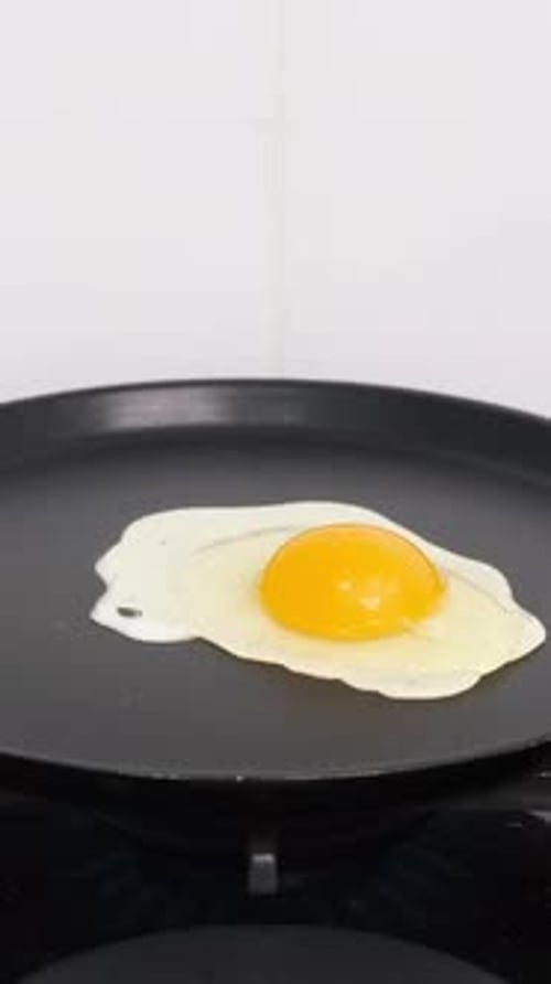 Ein Ei in einer Pfanne kochen, Spiegelei kochen (Vertikales Video)