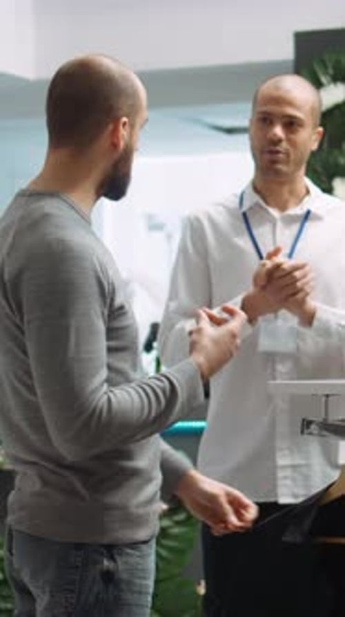 Vertical Video Mall Employee Assisting Customer to Choose From the New Collection of Clothes