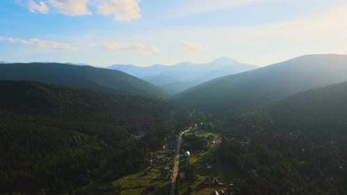Aerial View of Amazing Scenery with Small Village Houses Between Foggy Dark Mountain Peaks Covered