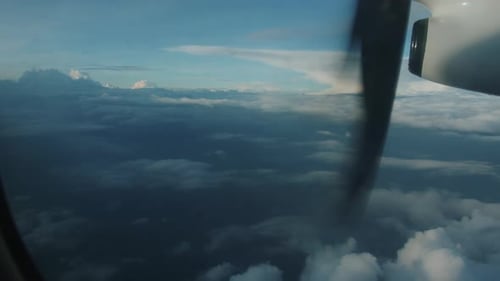 View From Window of Rotating Propeller of an Airplane Flying Above White Fluffy Clouds