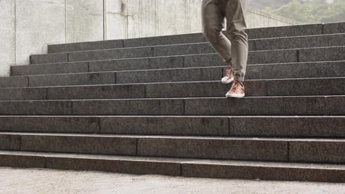 African American man descending stone steps at urban plaza, placing feet, preparing to walk forward