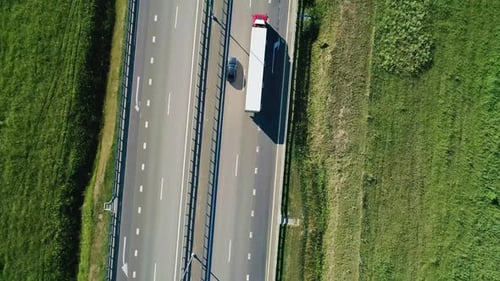 Aerial Top Down of Highway Through Green Meadows with Traffic on It on a Bright Sunny Day