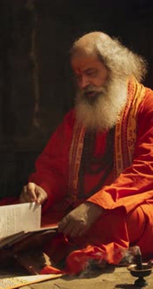 Man in Orange Robes Reads in Meditation